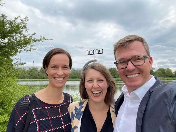 2 woman and a man in front of the Noma sign