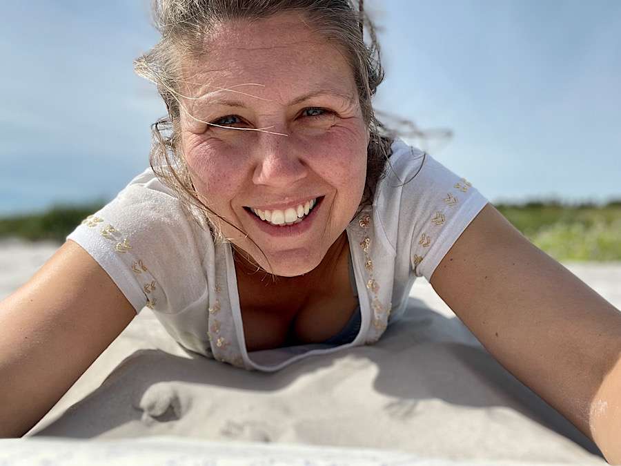 Woman lying on the sand, taking a selfie