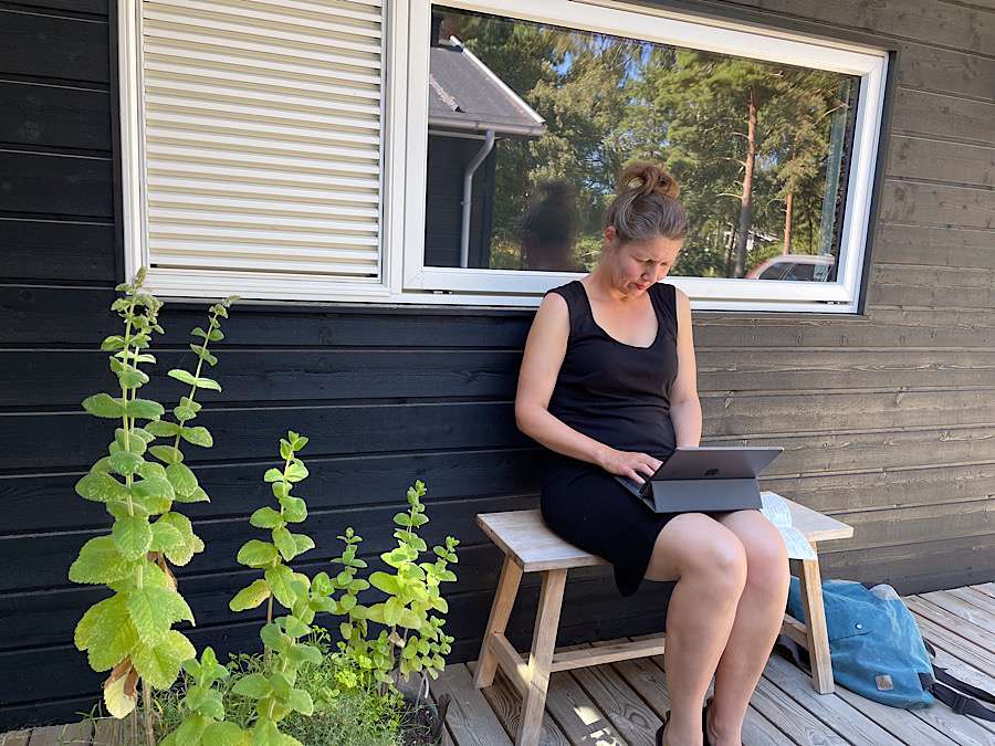 Woman sitting on a bench, typing her notes into an iPad