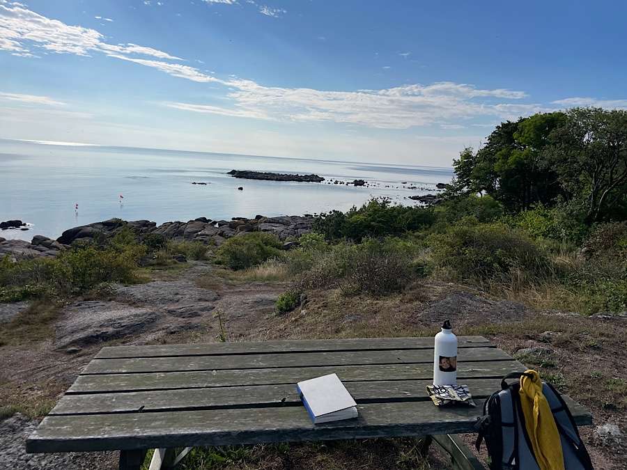 Notebook and water bottle on a wooden table overlooking the sea