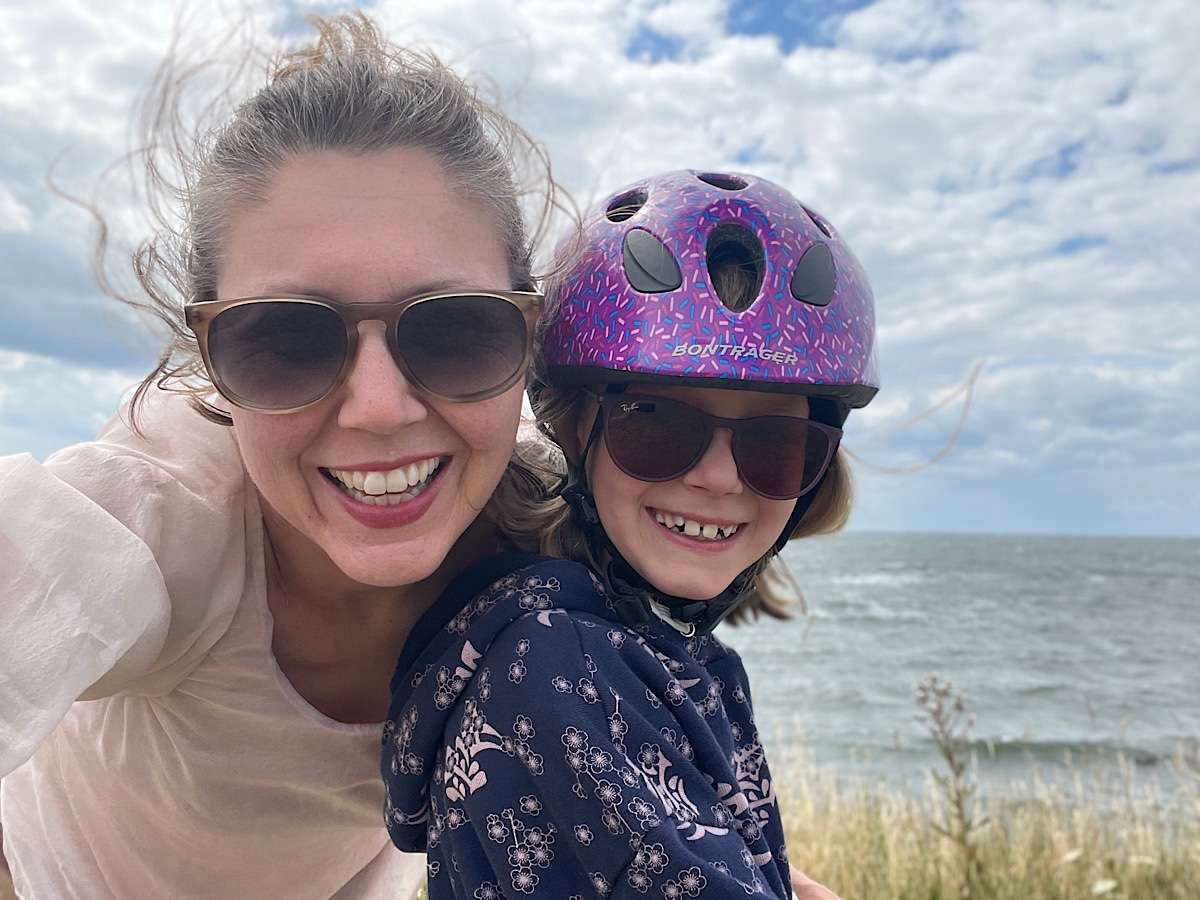 Mother and child with bike helmet in wind by seaside