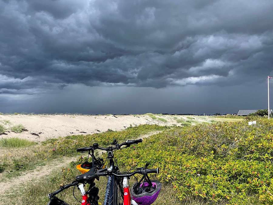3 bikes on the beach, dark clouds in background